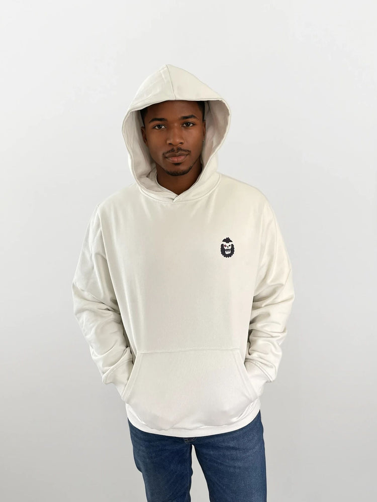 Man wearing a white hoodie with a Bigfoot 2099 design on the chest, showcasing a modern and stylish look.