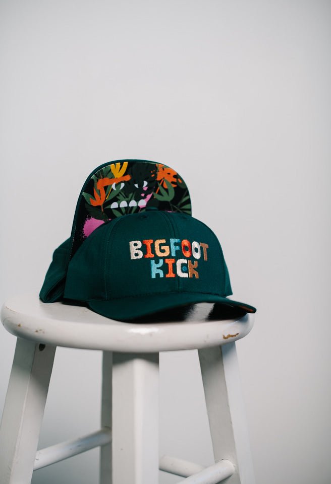Hidden Bigfoot Hat displayed on a stool showcasing its unique Bigfoot-themed design.