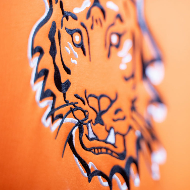 Close-up of the tiger design on the Squatchfuzz Tiger Hoodie, showcasing bold orange fabric and intricate embroidery.