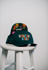Hidden Bigfoot Hat displayed on a stool showcasing its unique Bigfoot-themed design.